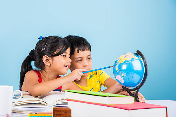 indian boy and girl studying with globe on study table, asian kids studying, indian kids studying geography, kids doing homework or home work, two kids studying on table